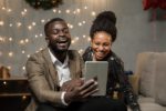 two black people looking at an iPad smiling